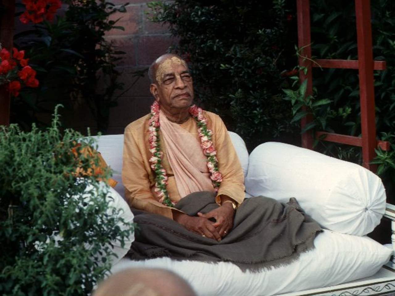 His Divine Grace A. C. Bhaktivedanta Swami Prabhupāda seated in a garden
